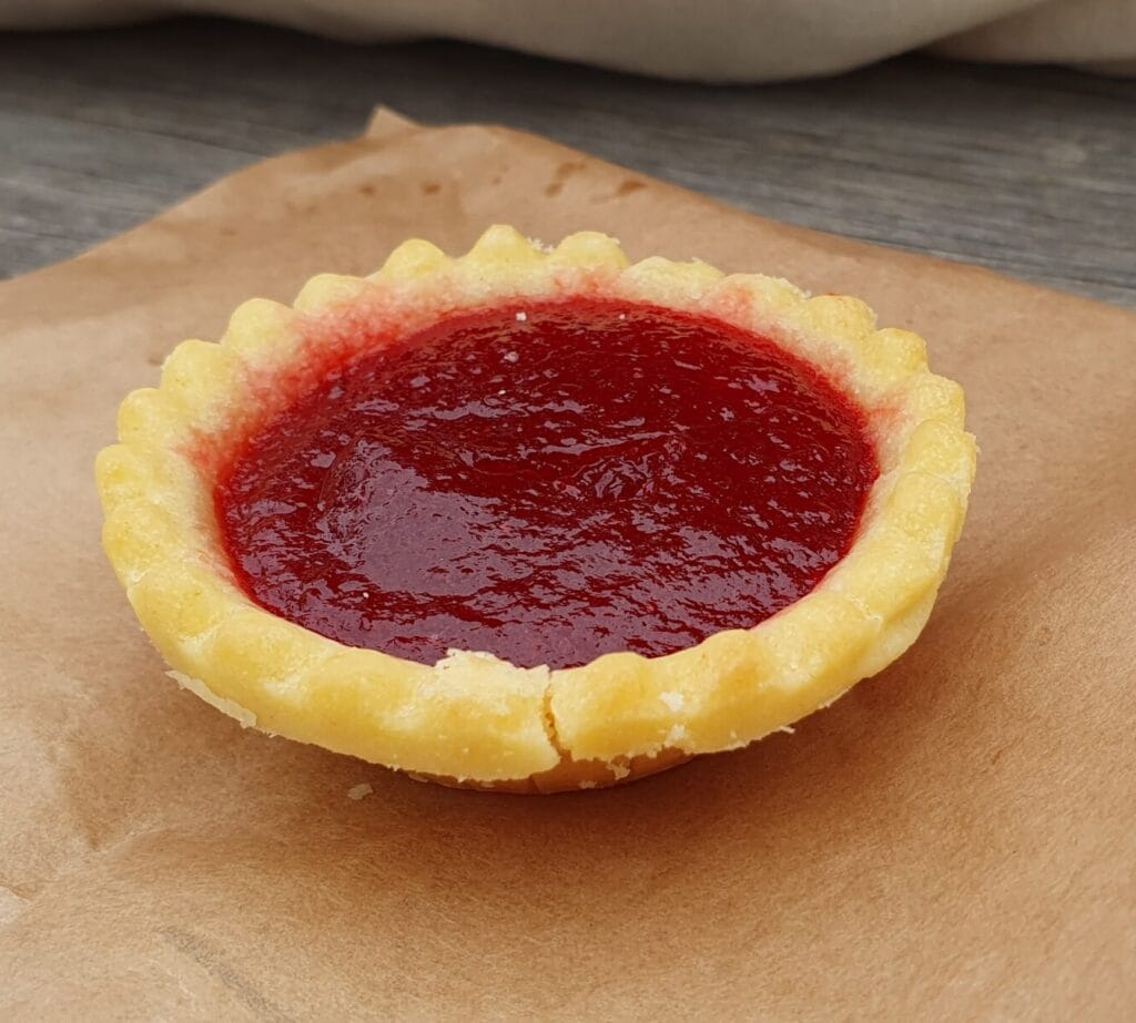 Aussie jam tart - sweet shortcrust pastry shell with a dollop of raspberry or other jam in the centre, baked until lightly golden.