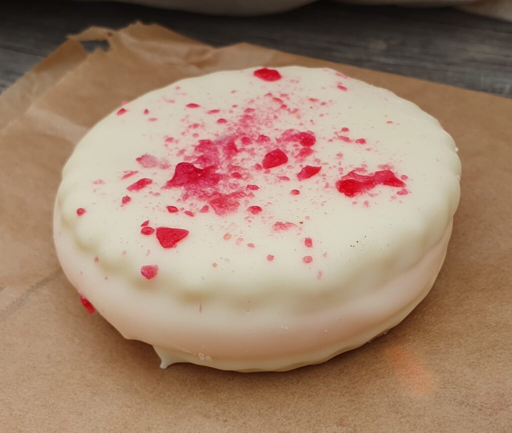 Sweet biscuit top and base, with a dollop of raspberry jam and smear of marshmallow to glue them together, then coated in white or milk chocolate.